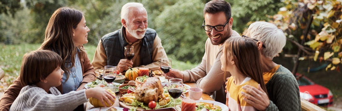 Multigenerational family eating dinner outside.
